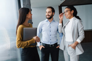 Portrait of successful colleagues holding papers and discussing business plans while working in office